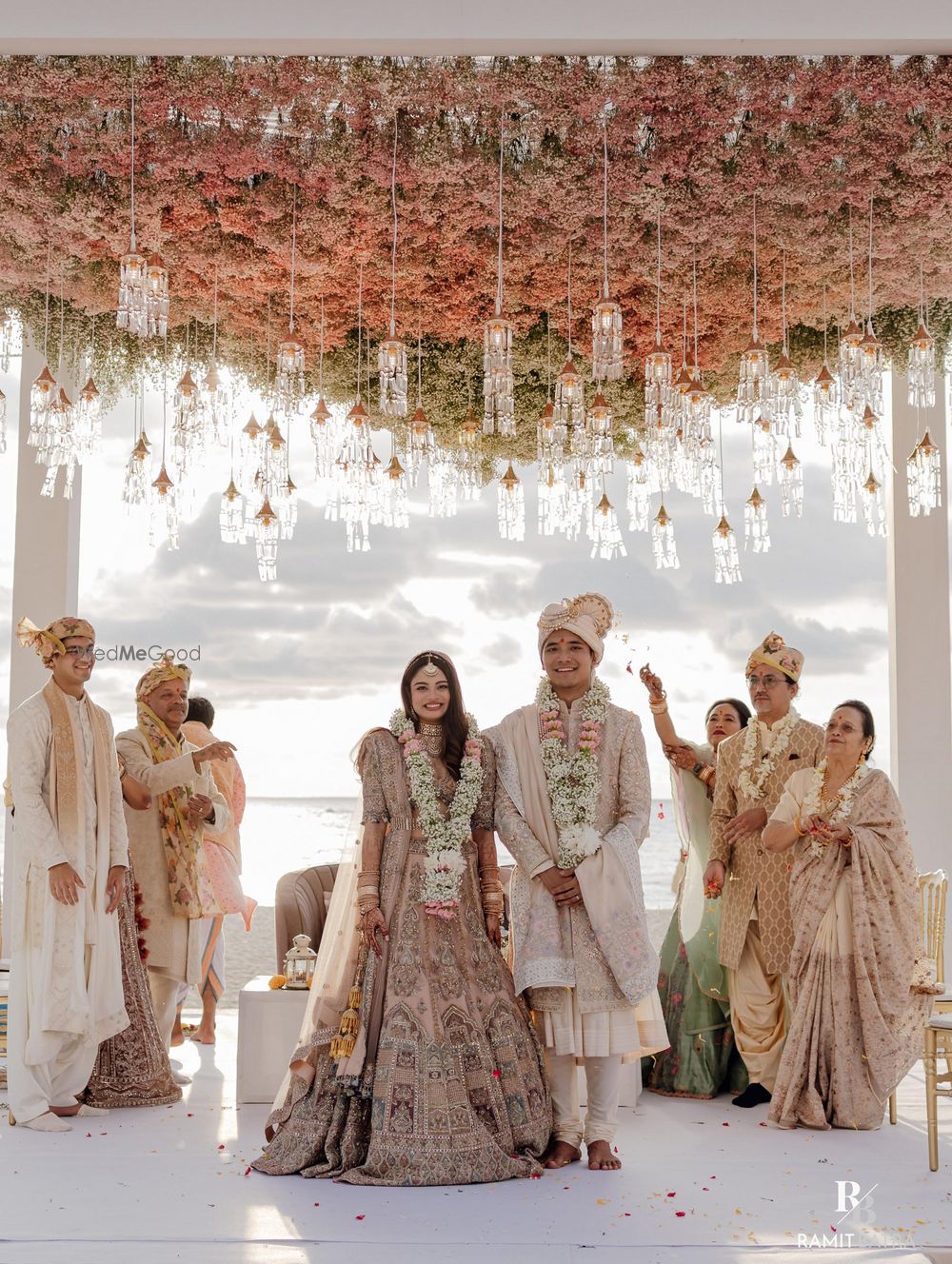 Photo of Stunning peach and white mandap for a beach side wedding with couple and family in pastels