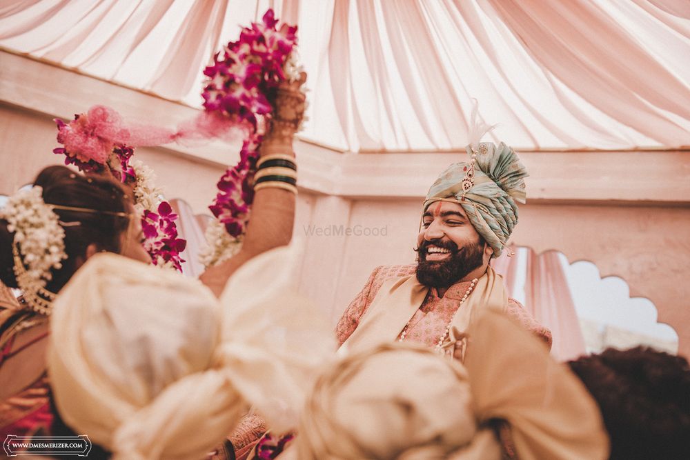 Photo of Bride trying to put the varmala on the groom while the groom's friends pick him up and pull him away