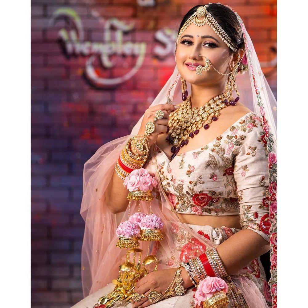 Photo of A happy bride in a lovely light pink lehenga with floral embroidery.