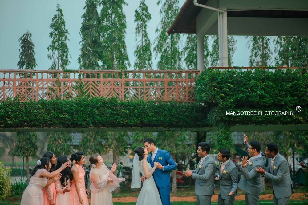 Photo of A Christian bride and groom kiss as their friends look on