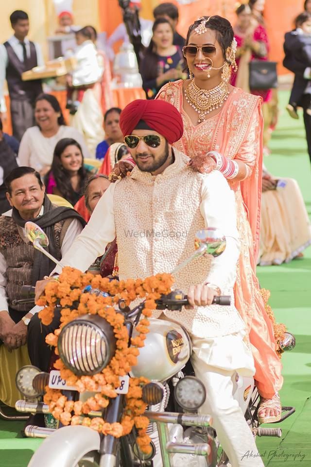 Photo of A sikh bride and groom enter the wedding venue on a bike