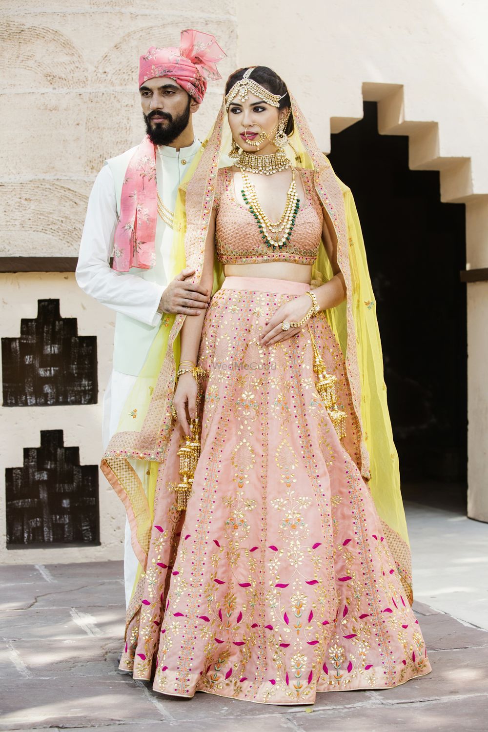 Photo of A bride and groom coordinate in white and pink on their wedding day