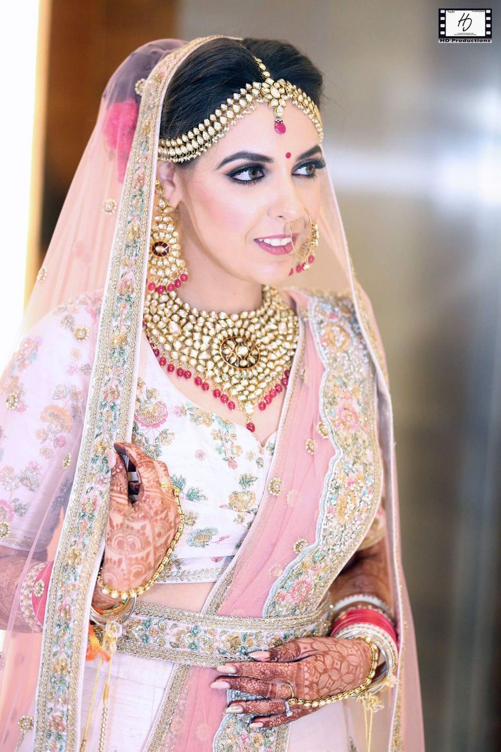 Photo of Pretty bride in pastel pink lehenga with gold jewellery