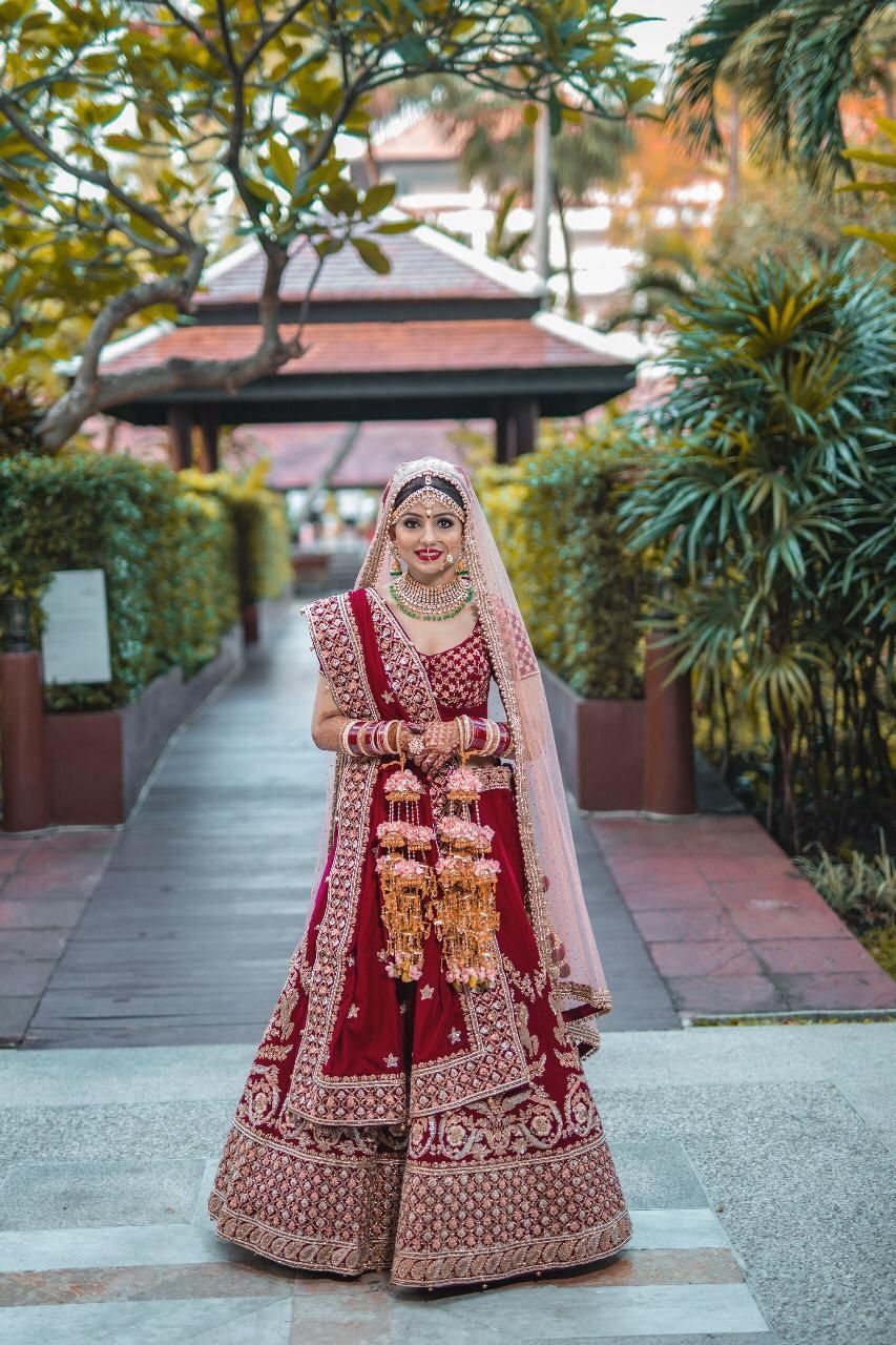 Photo of A bride in a classic maroon and gold lehenga with floral kalire