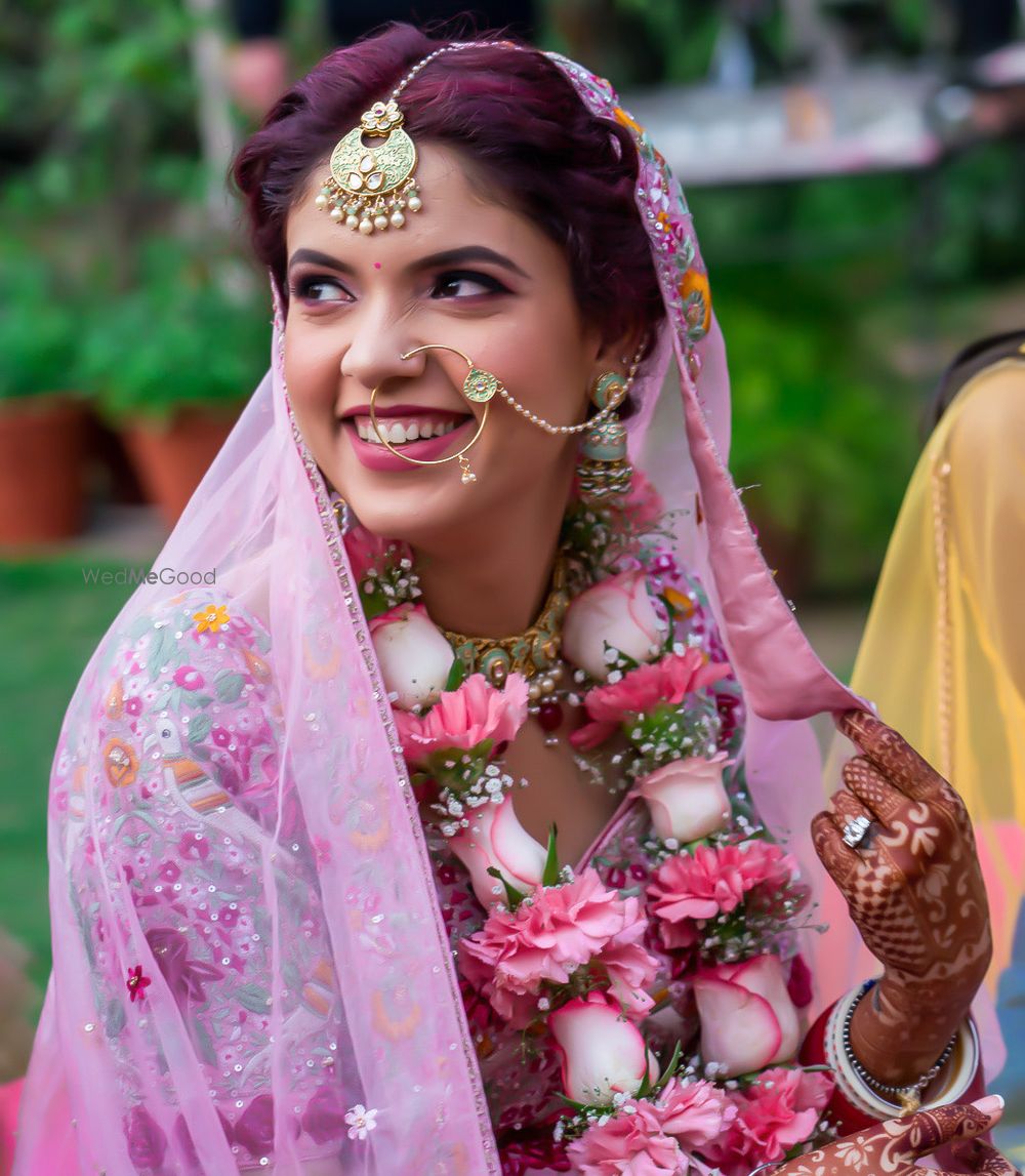 Photo of Candid shot of a bride wearing pink lehenga with green enameled jewellery.