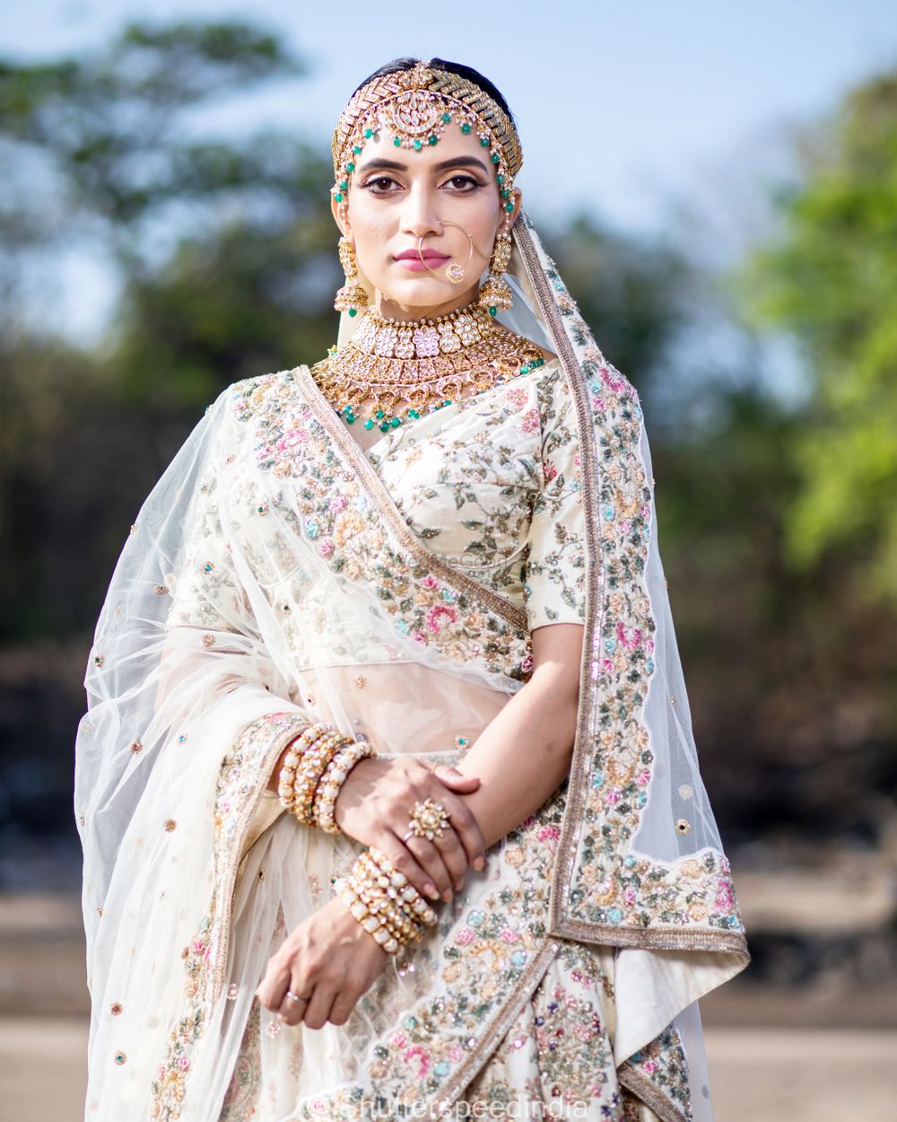 Photo of A bride in white with polki and jadau jewelry.