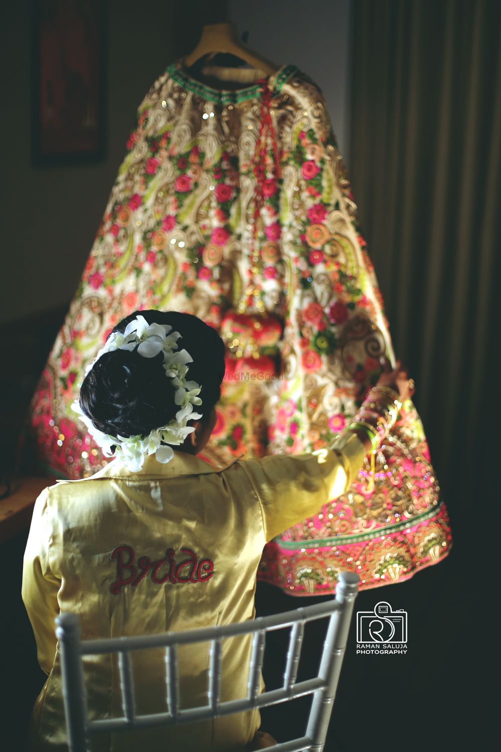 Photo of bride in robe holding her lehenga in her hand