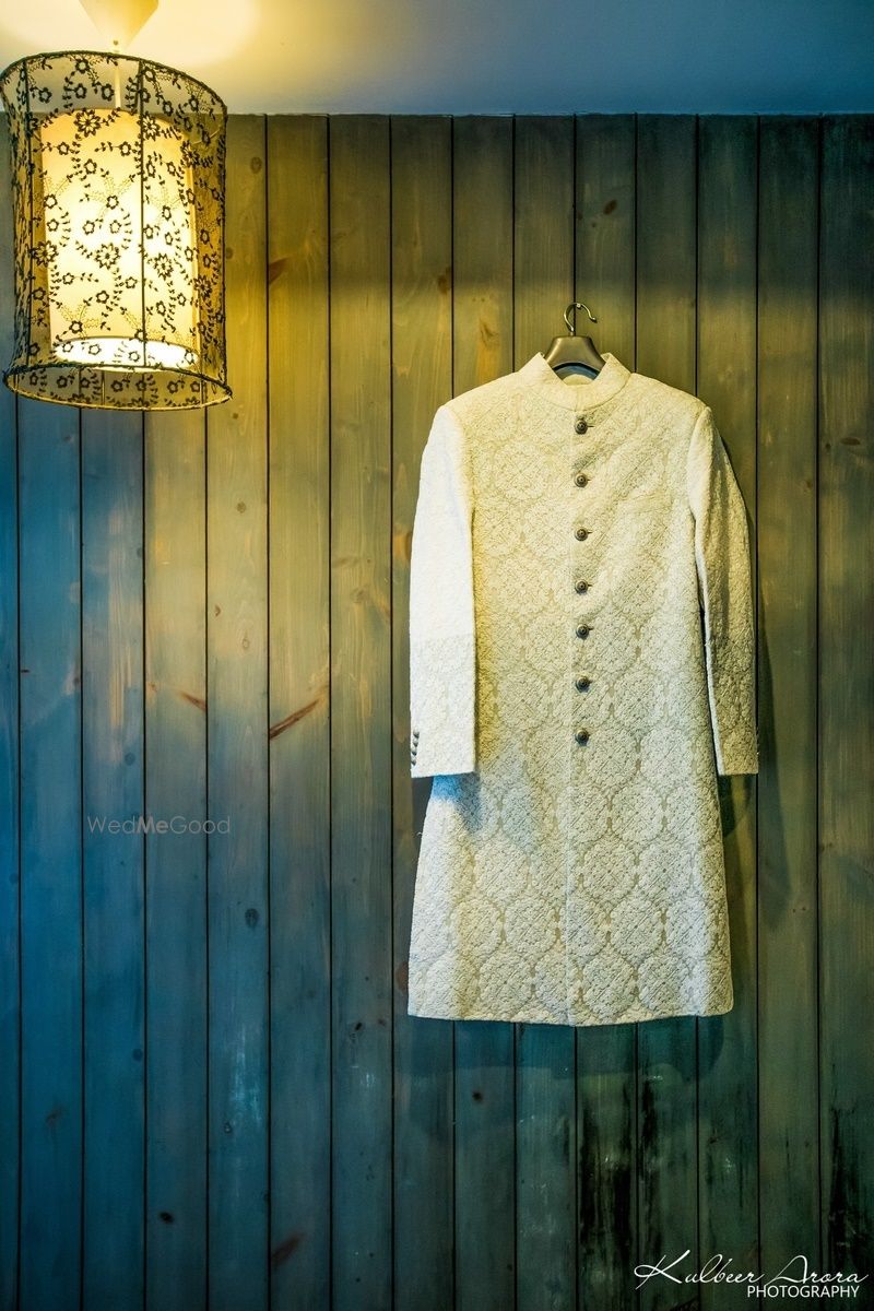 Photo of Beige sherwani on hanger on wooden wall