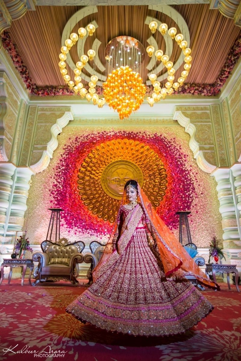 Photo of Twirling bride shot wearing red lehenga with grand backdrop