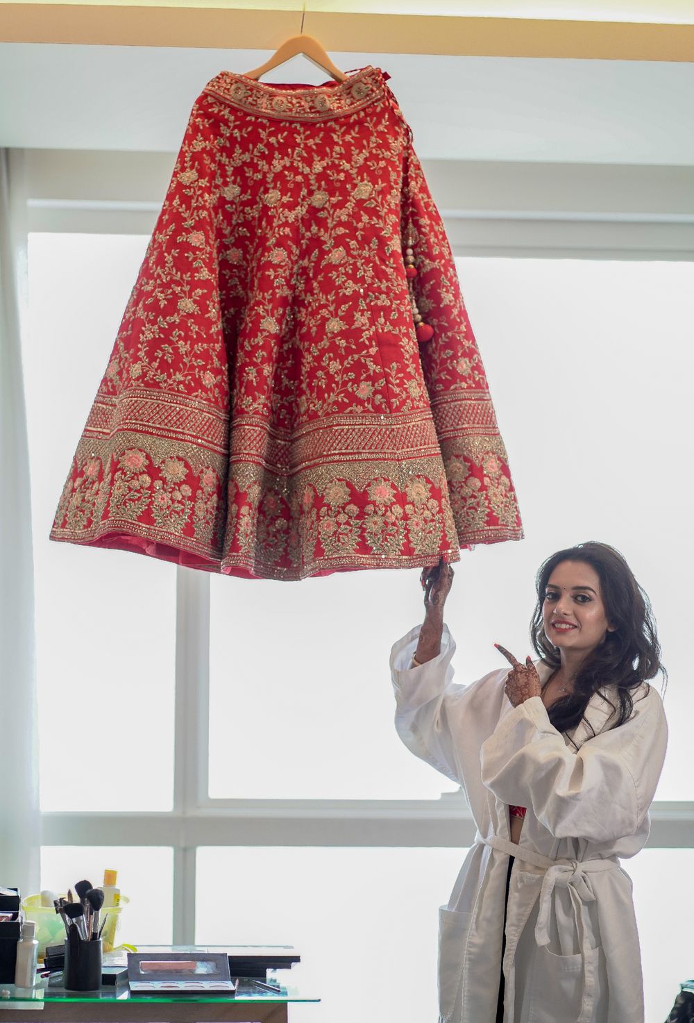 Photo of Bride with her lehenga on hanger in room shot