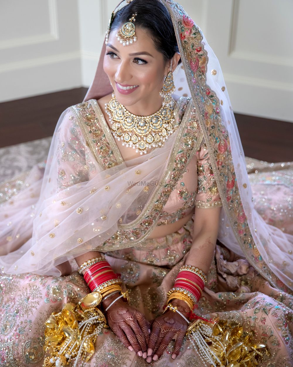 Photo of Bride in a light pink and gold lehenga with kaleere