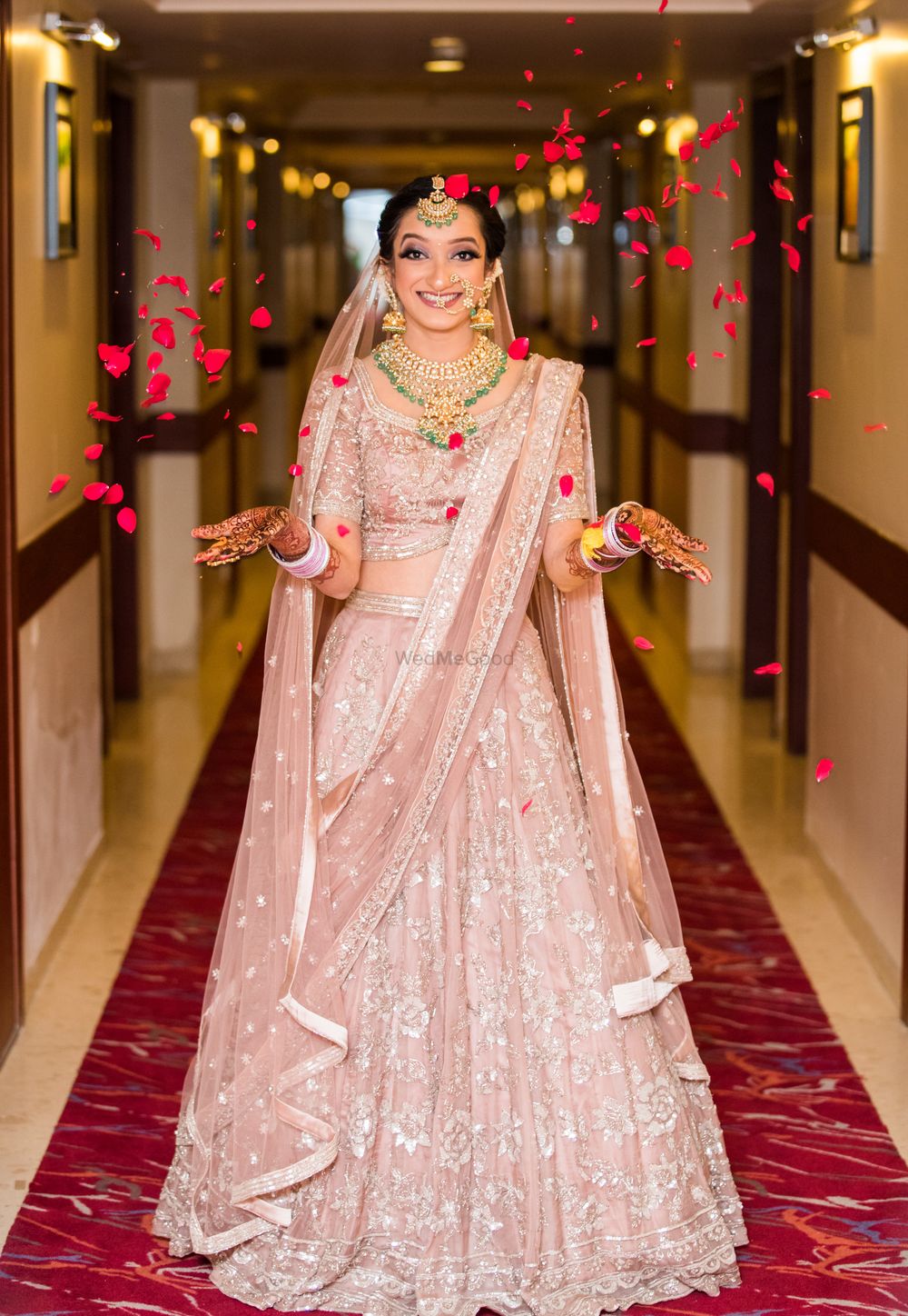 Photo of Happy bride in pastel pink lehenga and petals