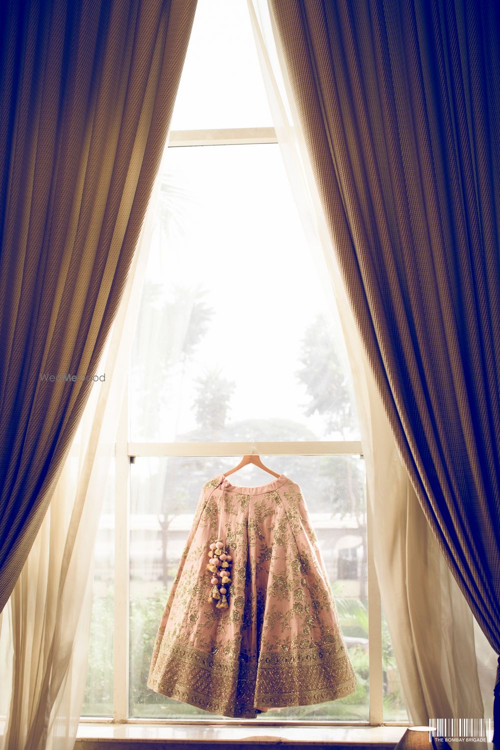 Photo of Peach and gold lehenga on hanger in window