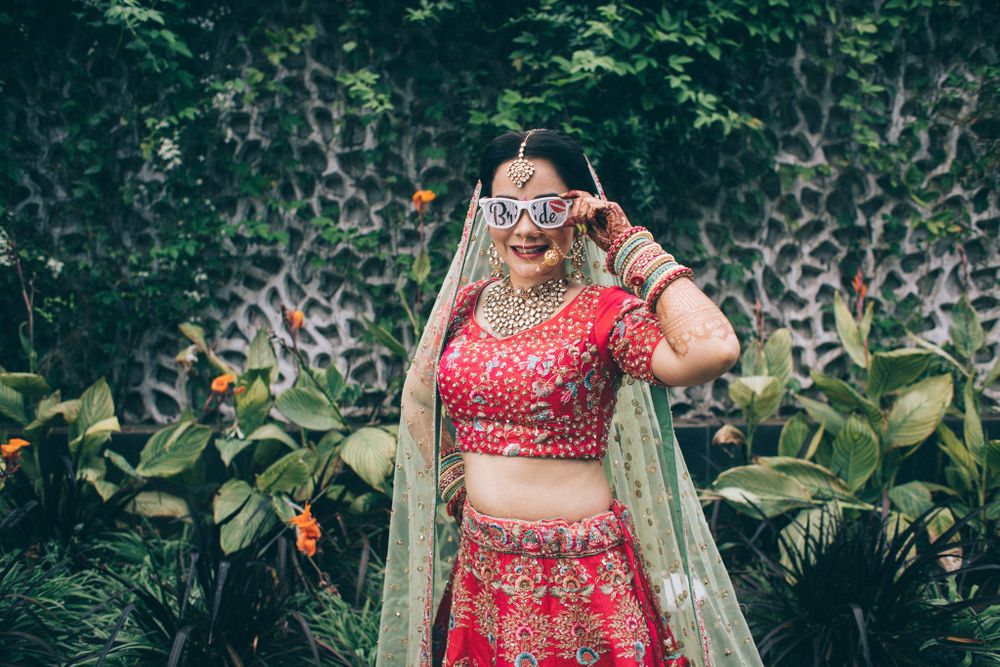 Photo of Bride wearing a sunglasses with a pretty red bridal lehenga