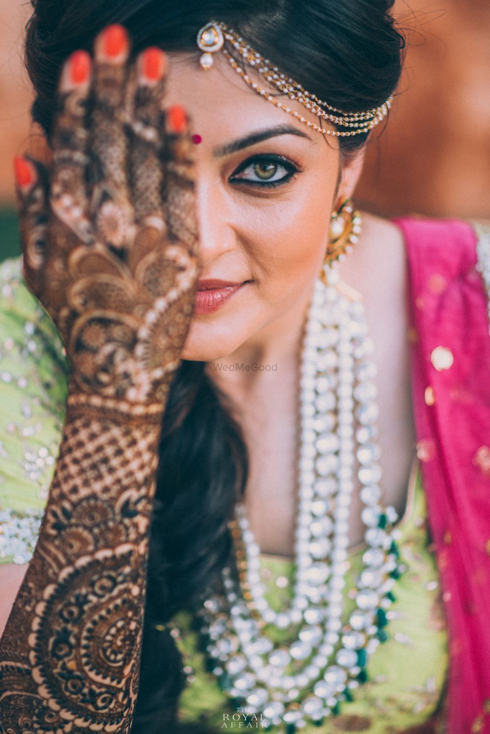 Photo of Bride showing off mehendi on hand covering face