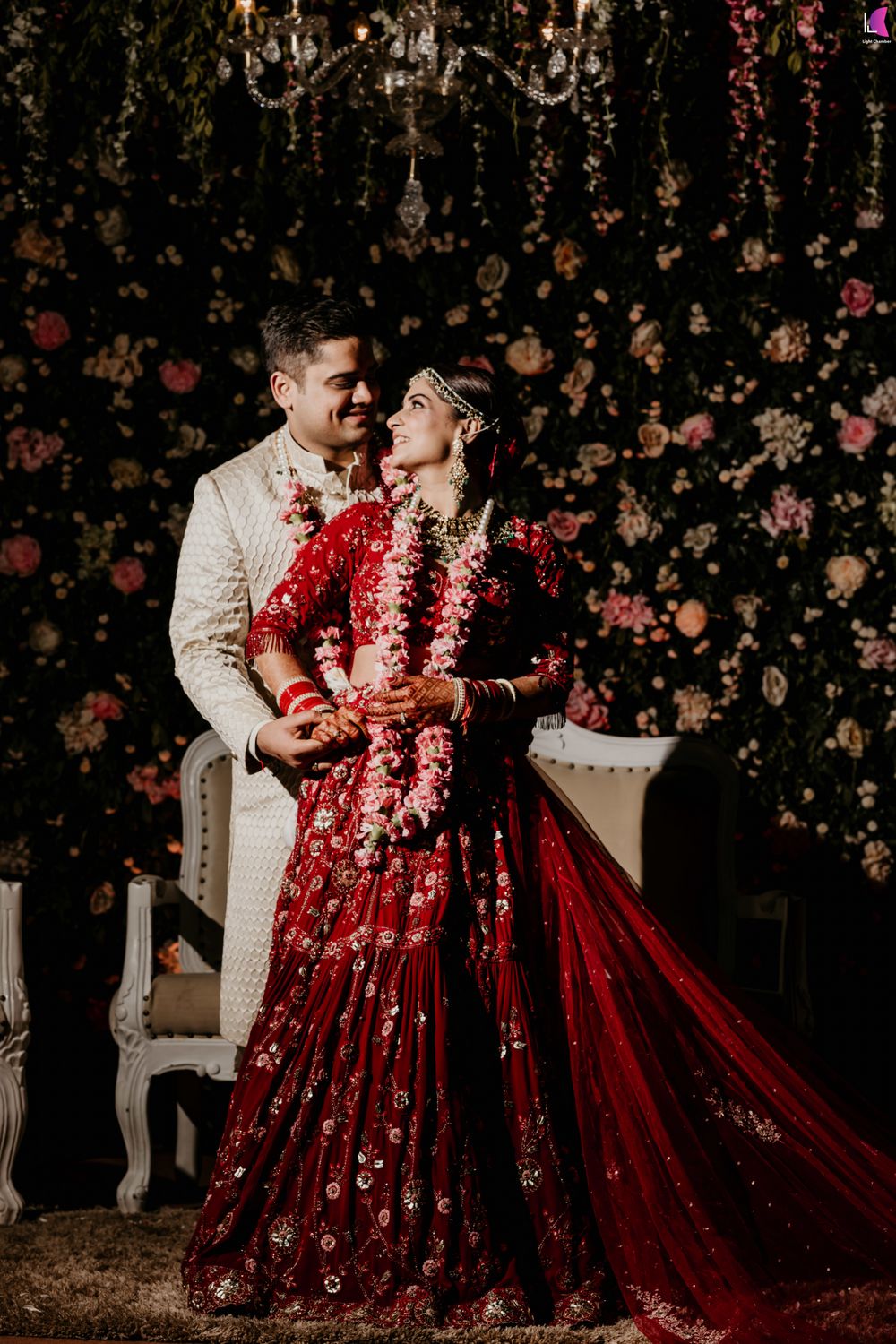 Photo of couple portrait in floral lehenga and against floral backdrop