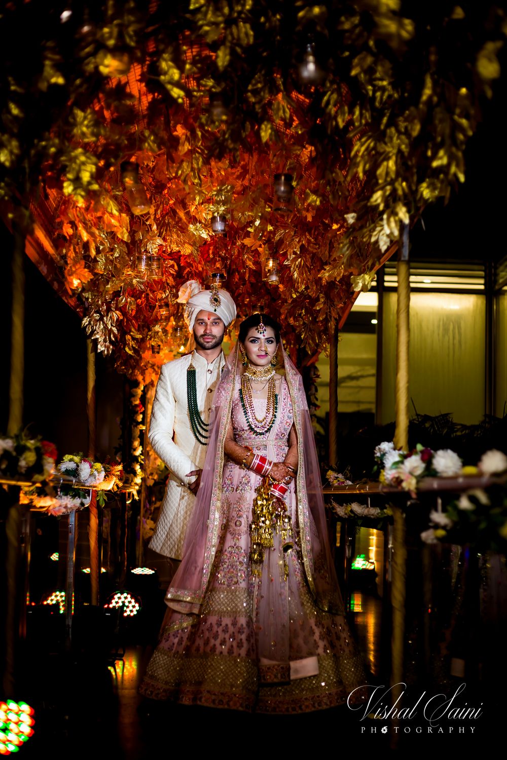 Photo of bride and groom against backdrop in pastel outfits