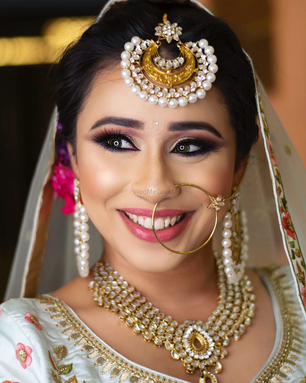 Photo of A happy bride in subtle makeup and gold jewellery.