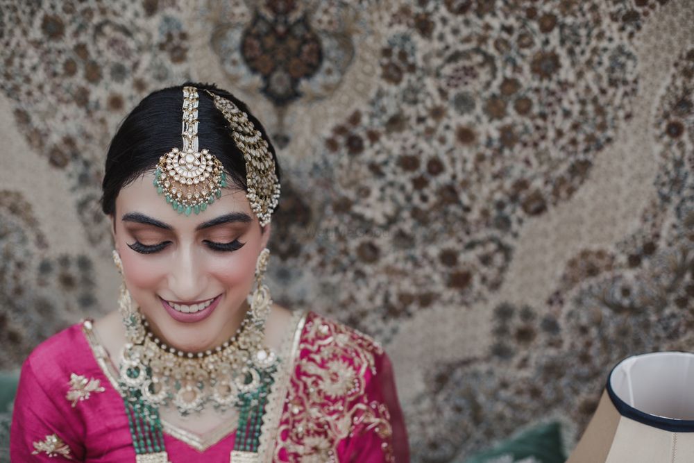 Photo of Bride wearing pink outfit with contrasting jewellery in green.