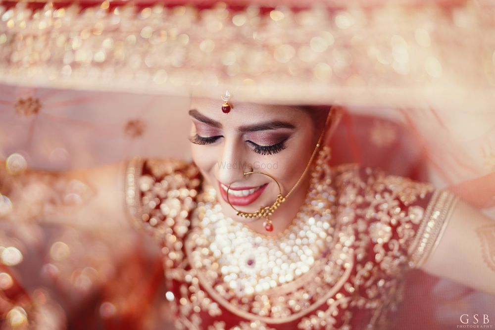 Photo of bride in red and gold holding her dupatta as veil shot