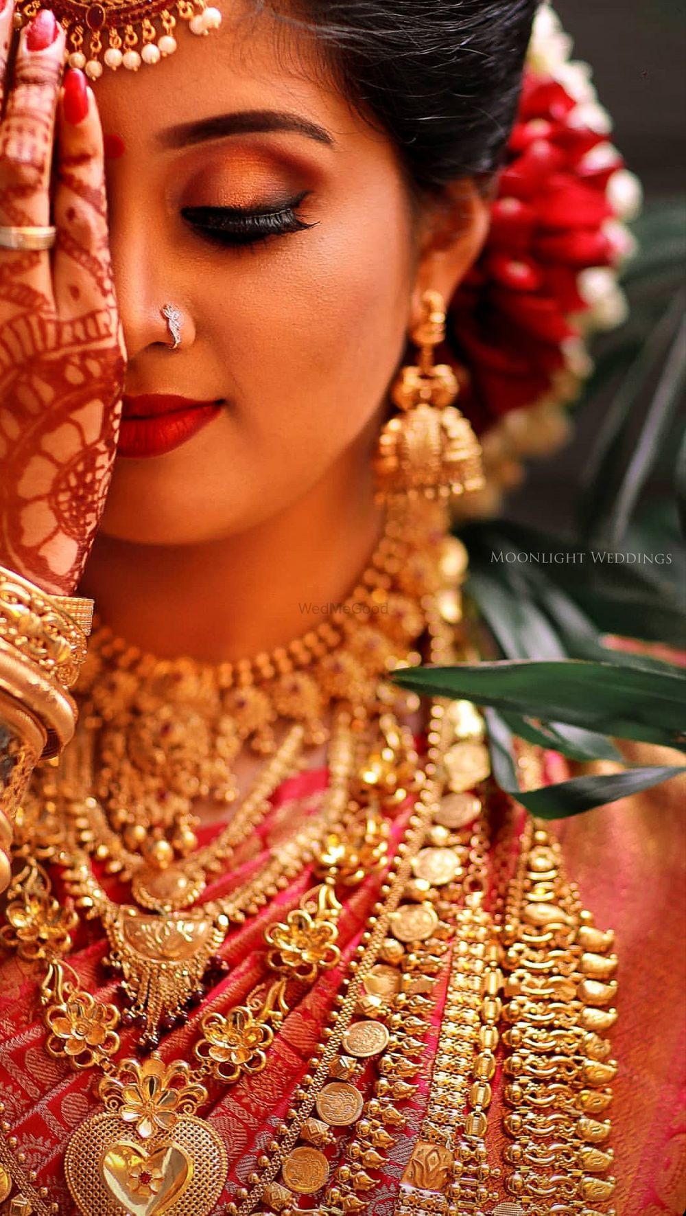 Photo of A bride wearing gold eye makeup and red lips on her wedding day