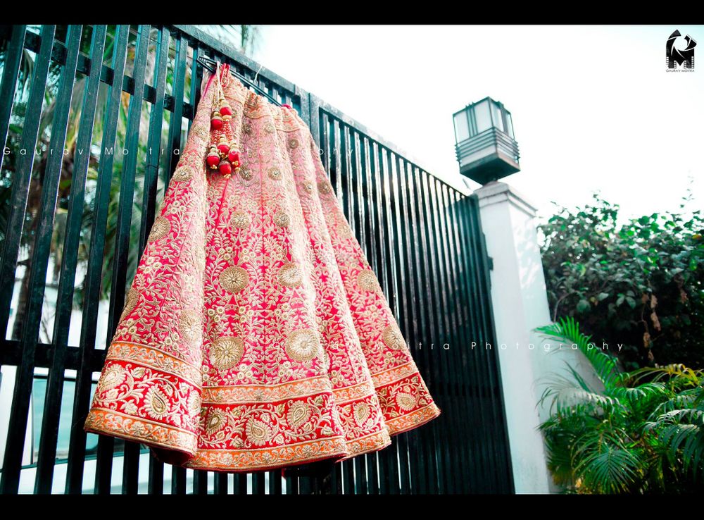 Photo of Bright Pink Lehenga with Red Border on Hanger on Gate