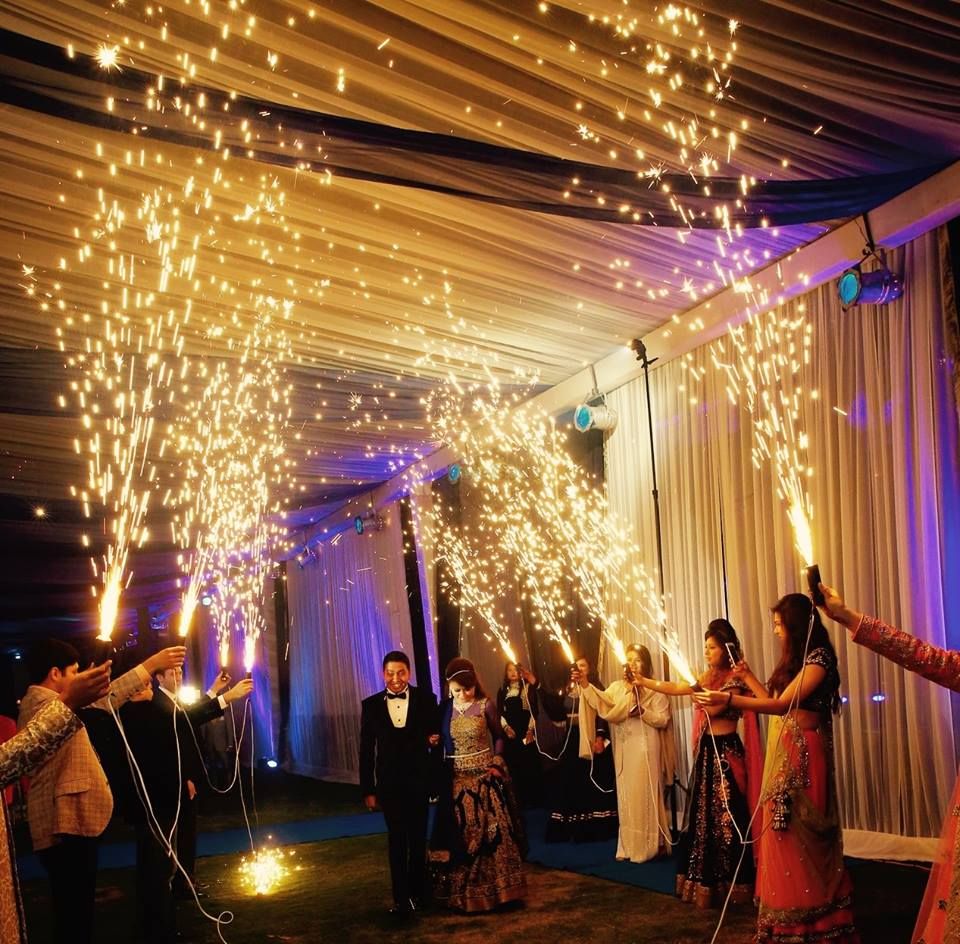 Photo of Bride and Groom Entering with Guests Holding Cold Pyro