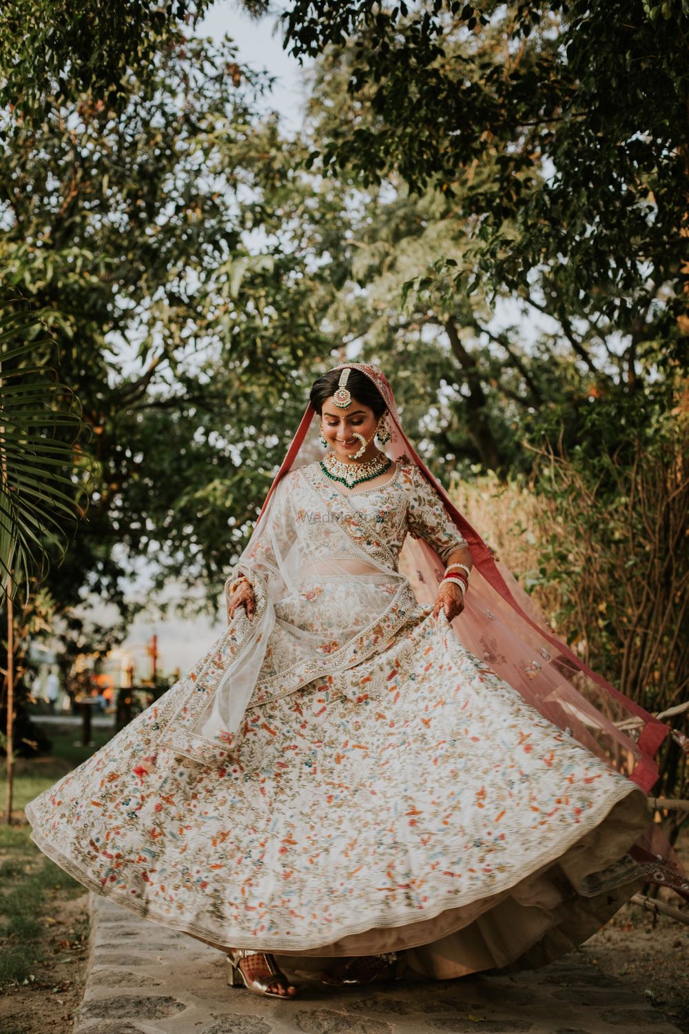 Photo of A bride in a white lehenga twirling on her wedding day