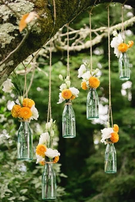 Photo of Hanging glass bottles filled with flowers.