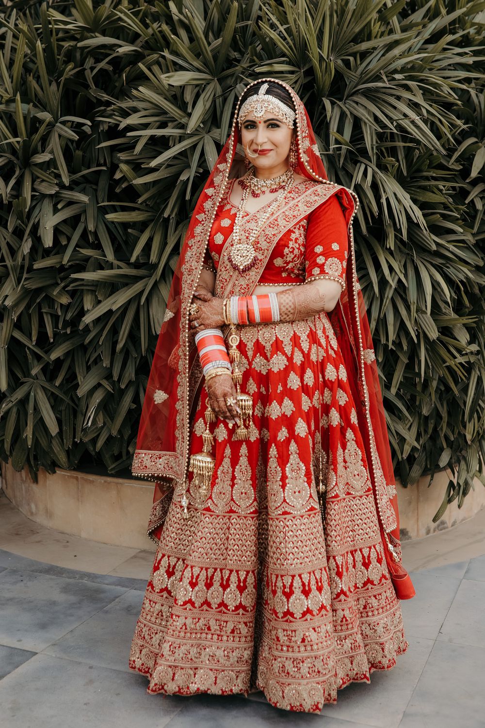 Photo of Bride in red and gold lehenga outdoors