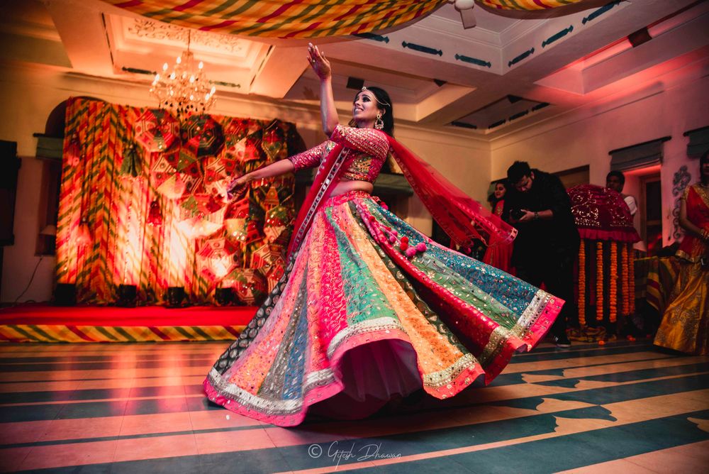 Photo of A bride in a multicolored lehenga dancing on her mehendi
