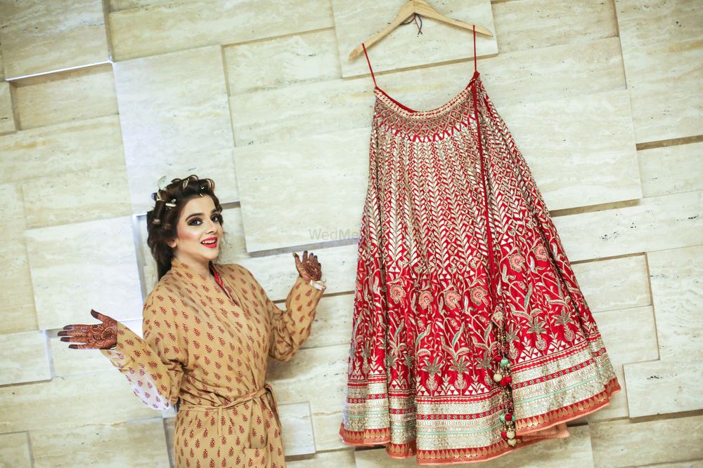 Photo of Bride with a Red Bridal Lehenga on a Hanger