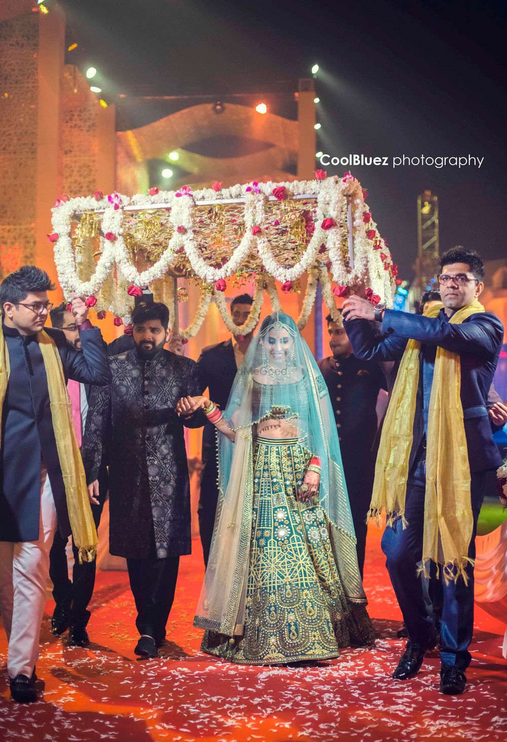 Photo of A bride in green enters under a phoolon a chaadar
