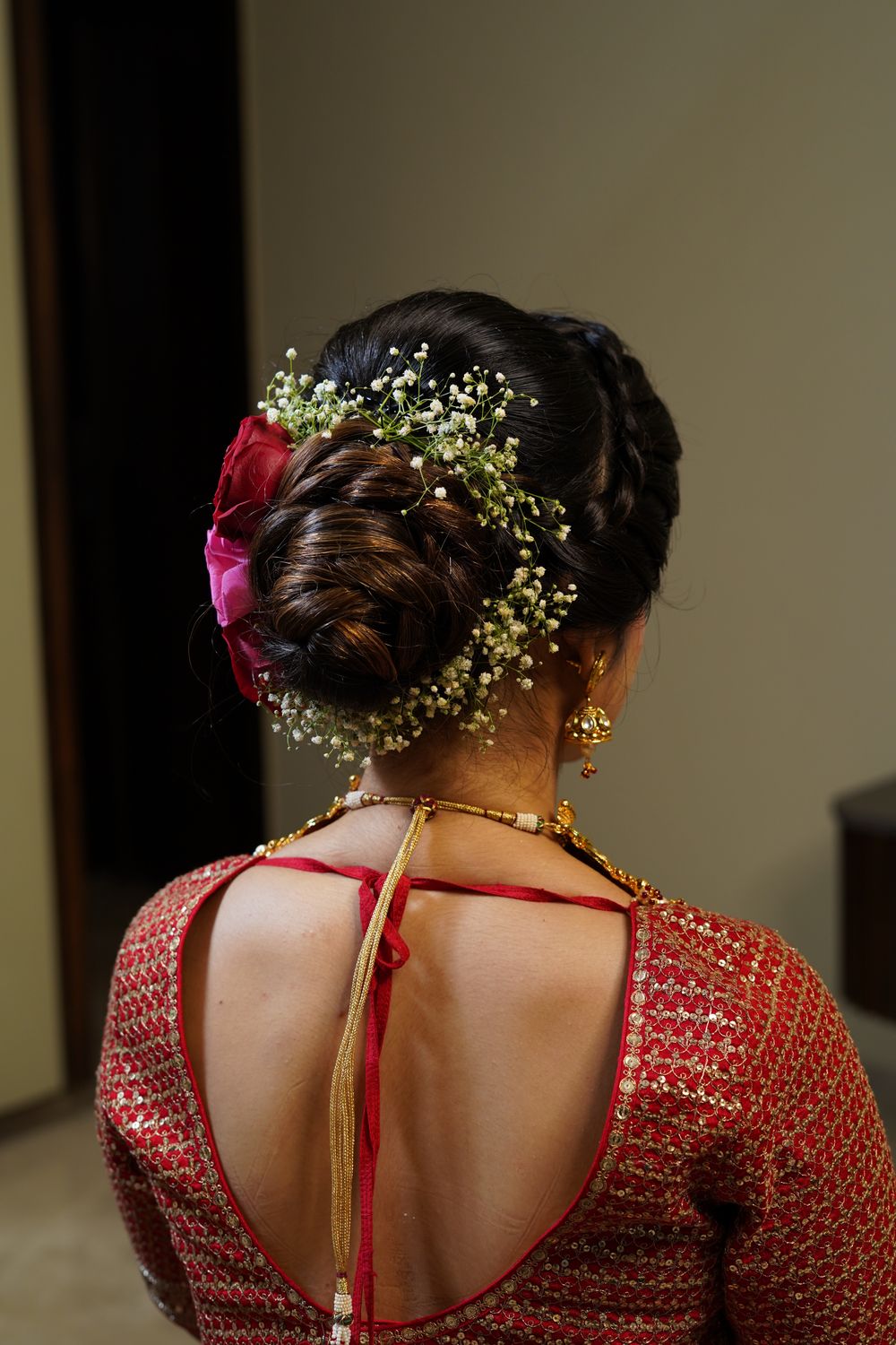Photo of A twisted bridal bun adorned with baby's breaths & roses.