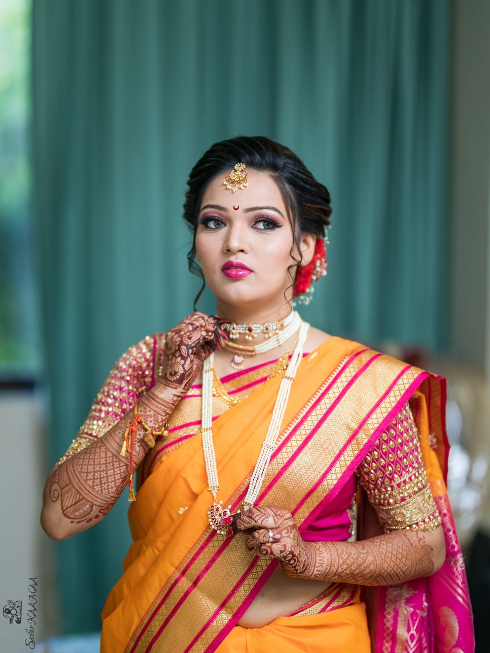 Photo of Marathi bride wearing an orange saree with a pink blouse.