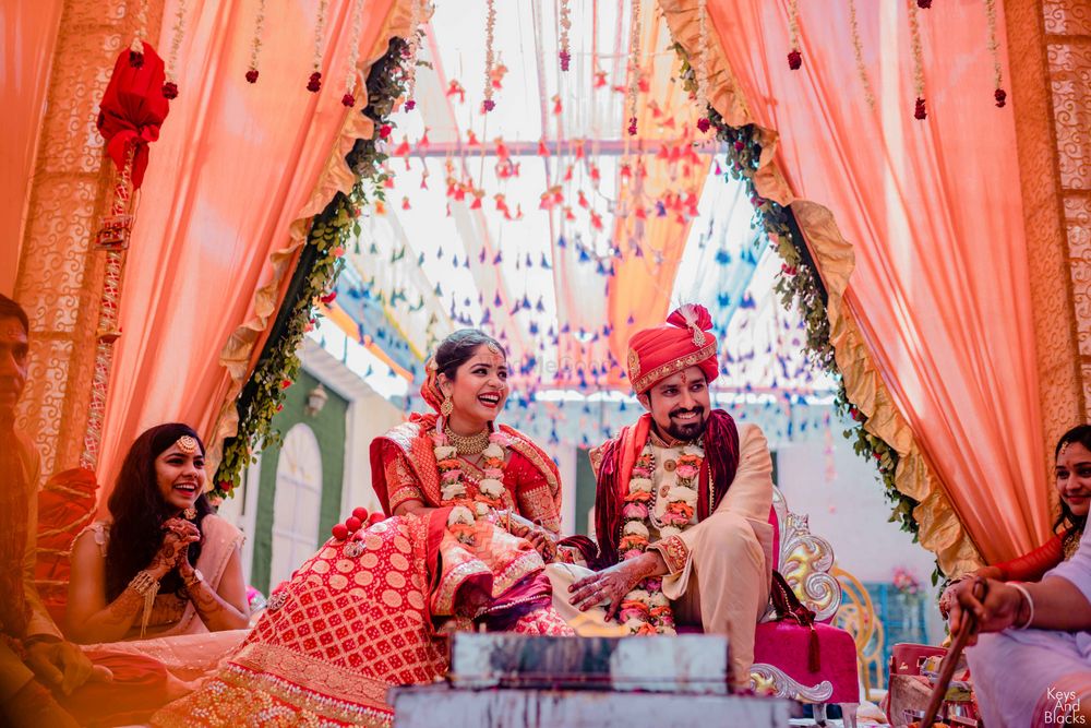 Photo of happy couple shot with mandap with peach drapes