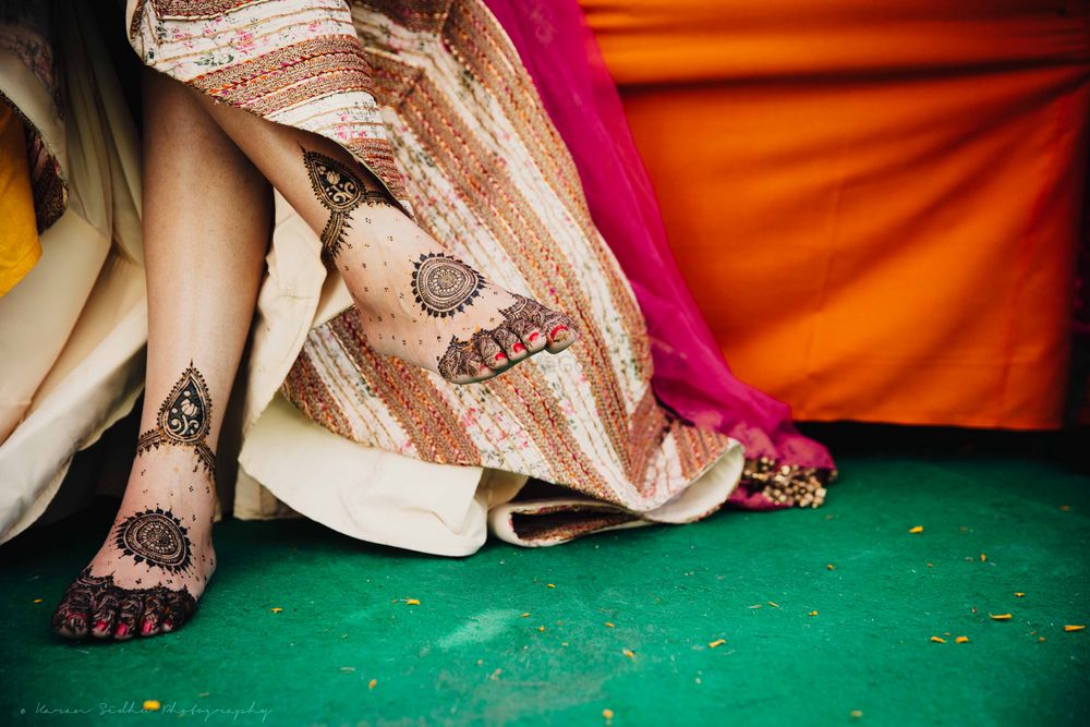 Photo of Bride sitting cross legged showing mehendi on feet