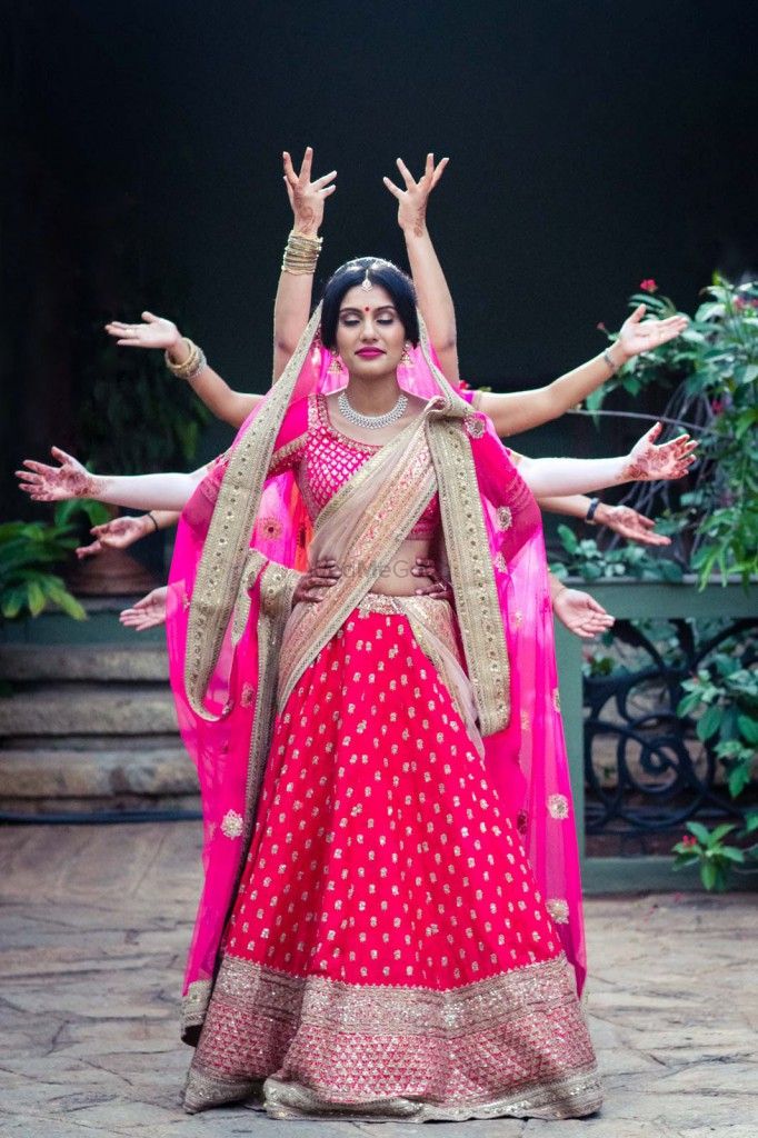 Photo of Bride in hot pink lehenga with hands sticking out