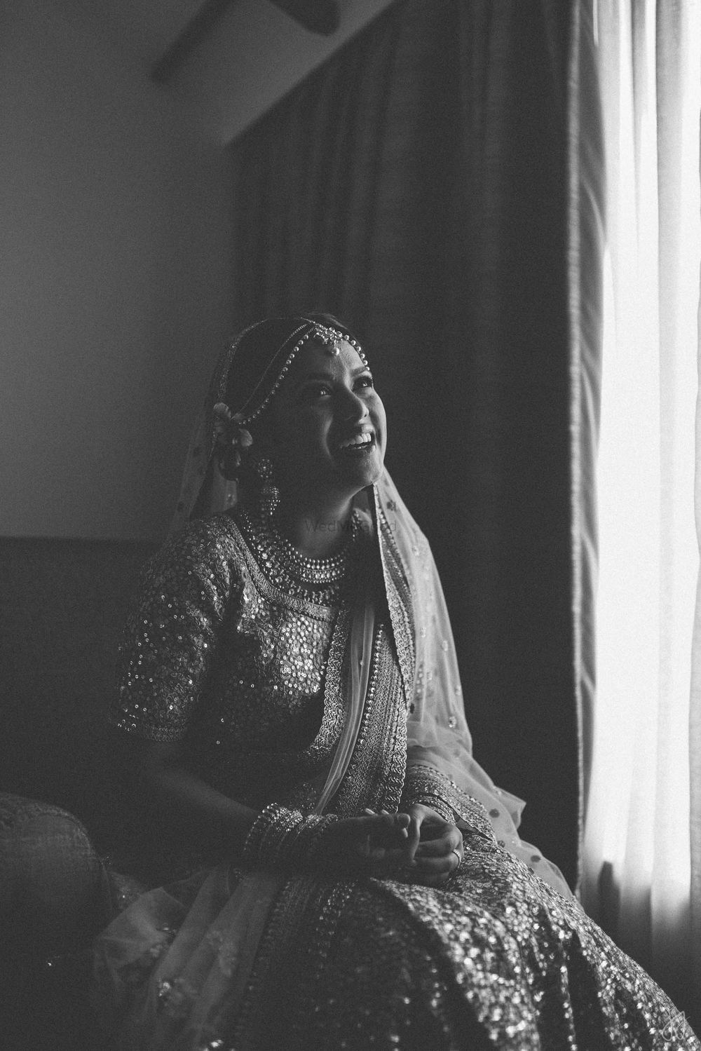Photo of Black and white bridal candid portrait next to window