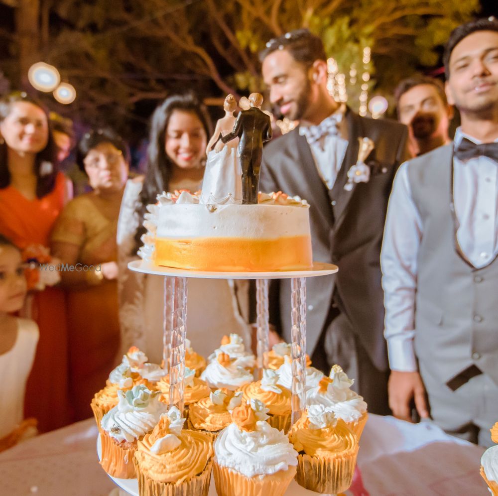 Photo of Orange and white wedding cake with cupcakes