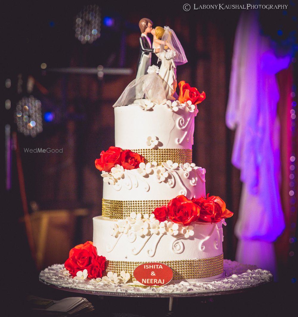 Photo of White wedding cake with couple topper and red roses