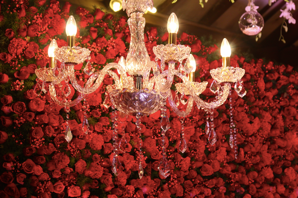 Photo of Hanging chandelier against floral wall backdrop