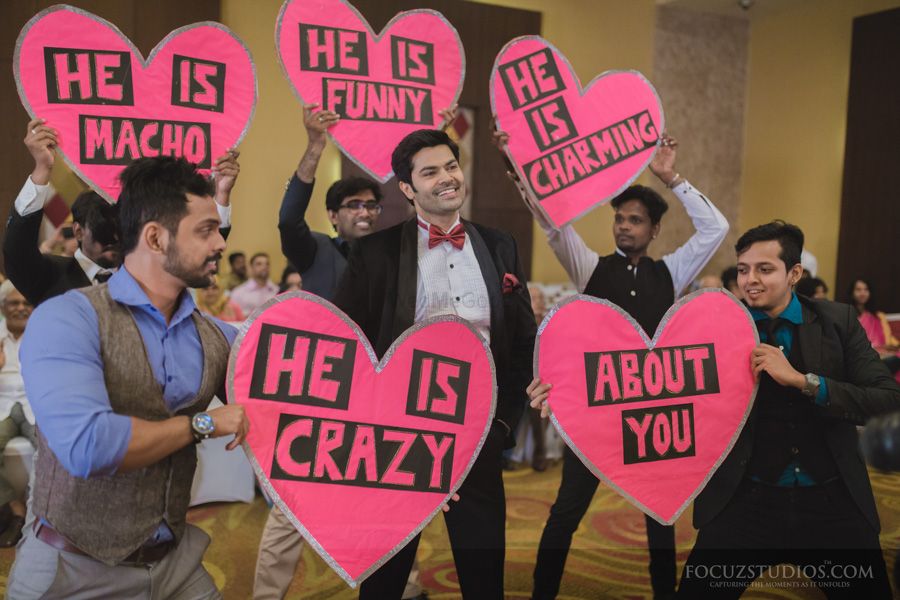 Photo of grooms men holding cute signage boards