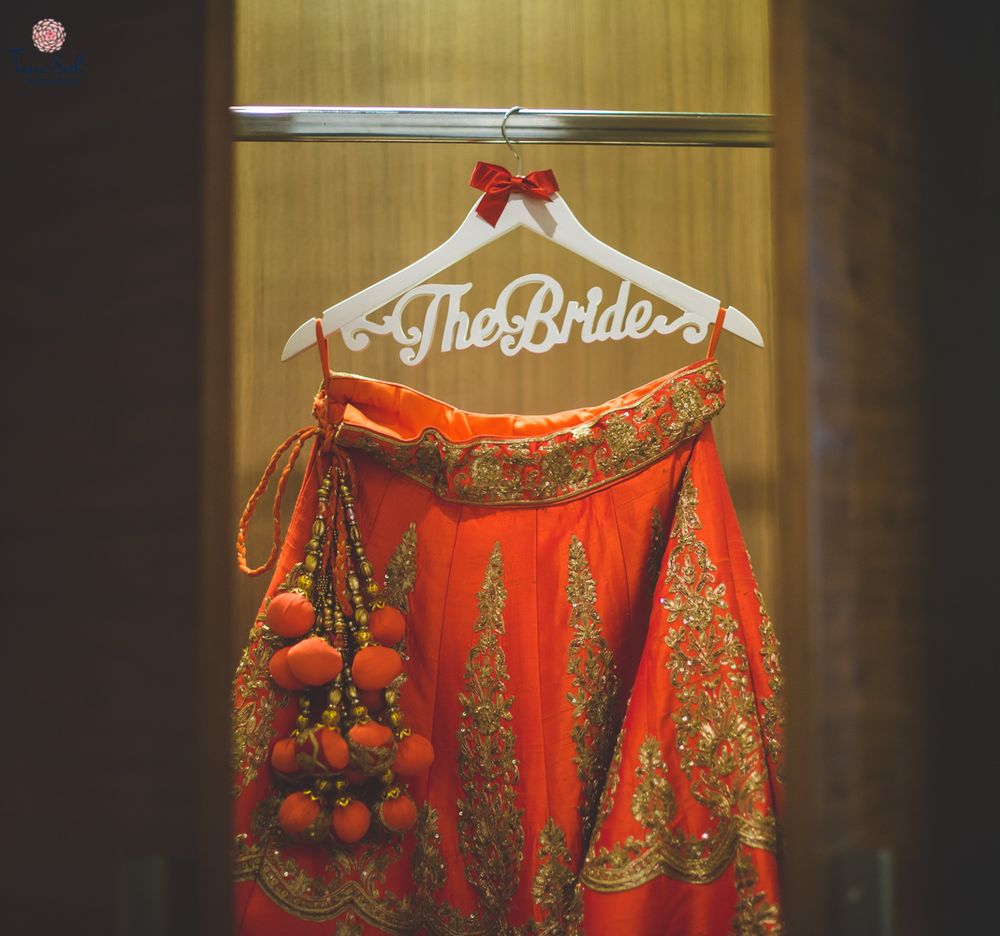 Photo of Red and gold lehenga hanging on customised bridal hanger