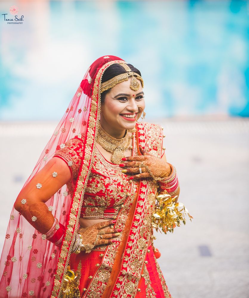 Photo of Bride in red and gold lehenga with kaleere and gold jewellery