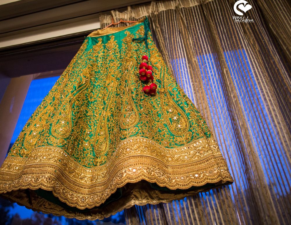 Photo of Green and gold lehenga on hanger in room