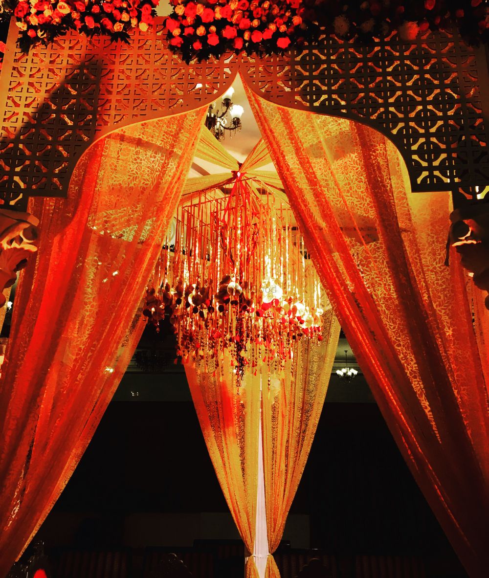 Photo of Unique mandap decor in orange and gold with hanging gota strings