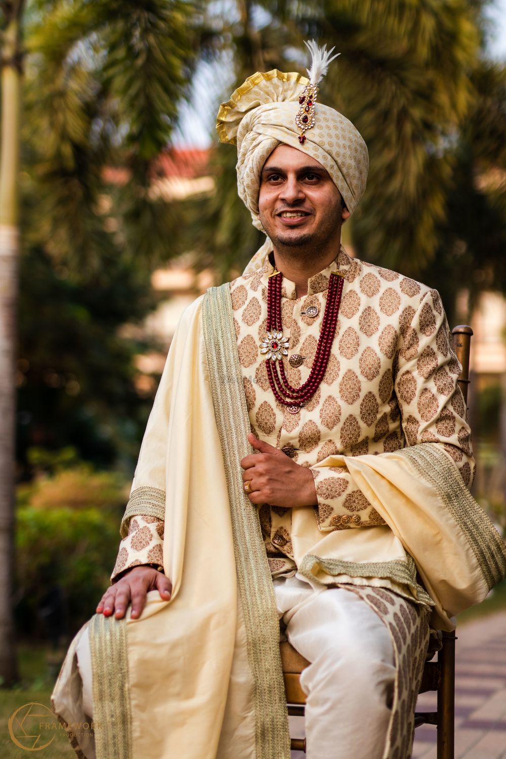 Photo of A happy portrait of a groom dressed in a classic white & gold sherwani