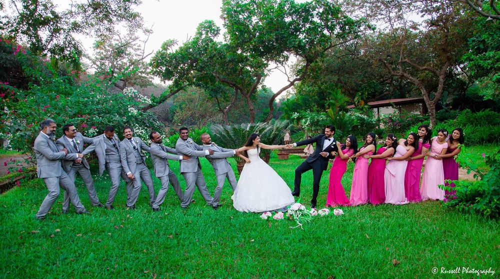 Photo of Couple playing tug of war with bridesmaids and groomsmen