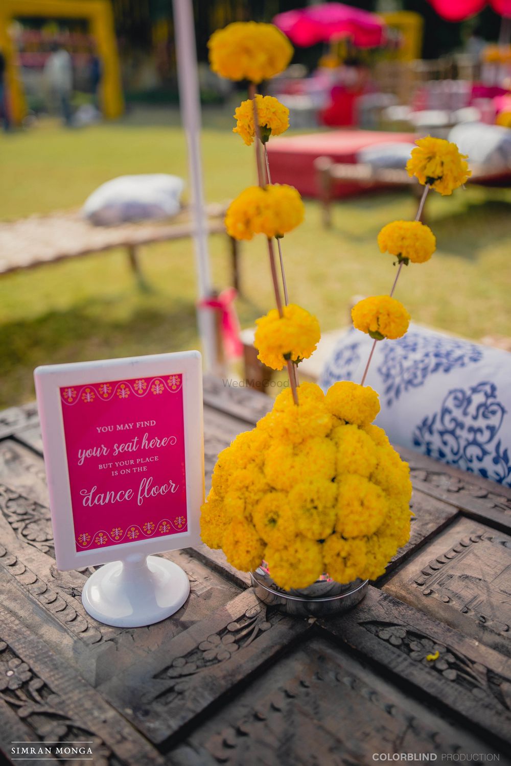 Photo of Mehendi table setting with floral centerpiece and dance floor sign
